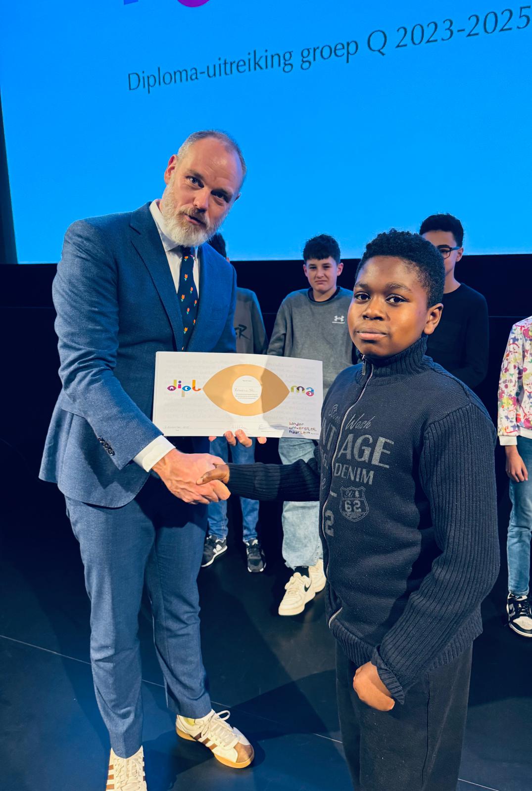 Een leerling ontvangt zijn diploma bij Kinderuniversiteit Haarlem